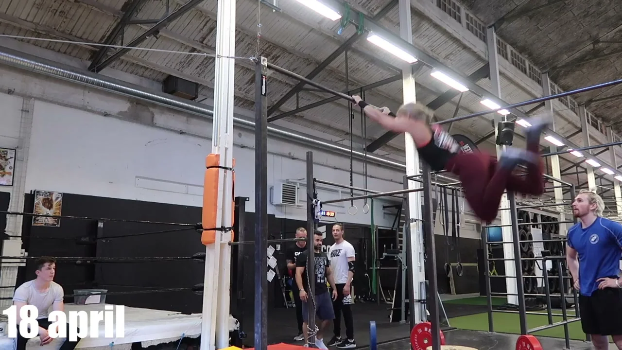 Malin Malle mid-air during a swing 540 rotation, body fully extended above the bar